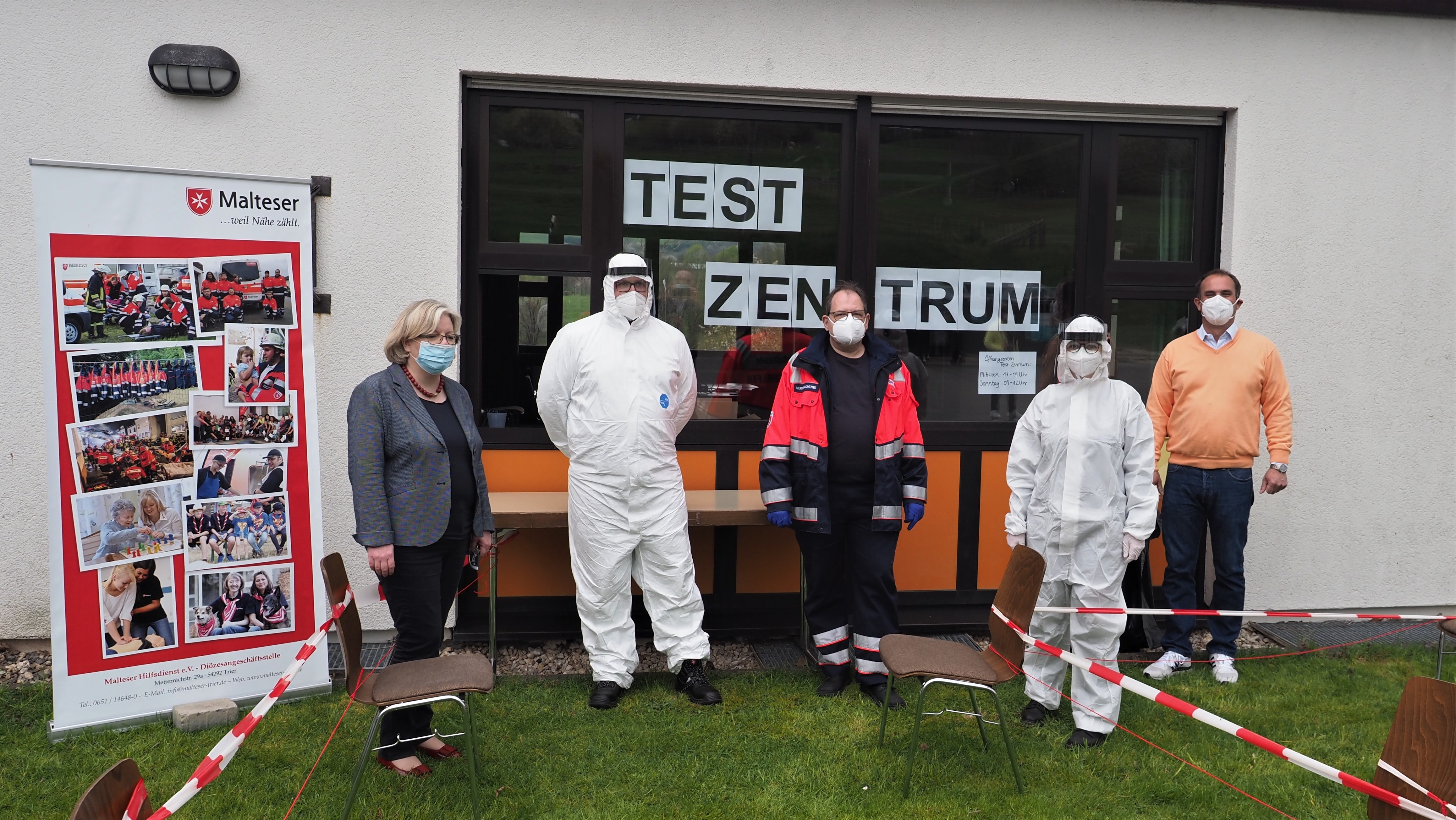 Menschen mit Masken vor Corona Testzentrum