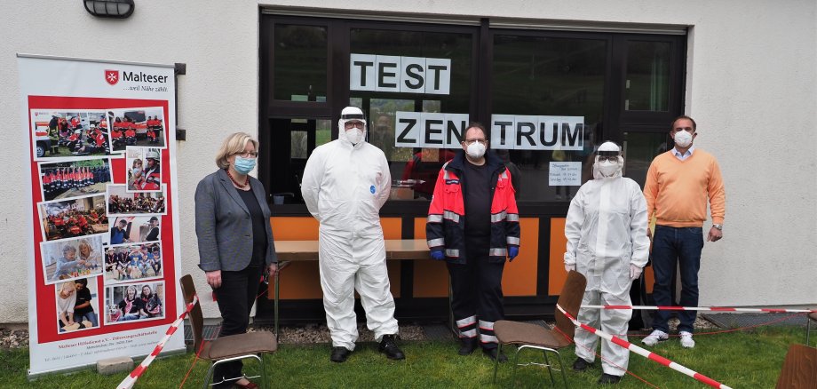 Menschen mit Masken vor Corona Testzentrum
