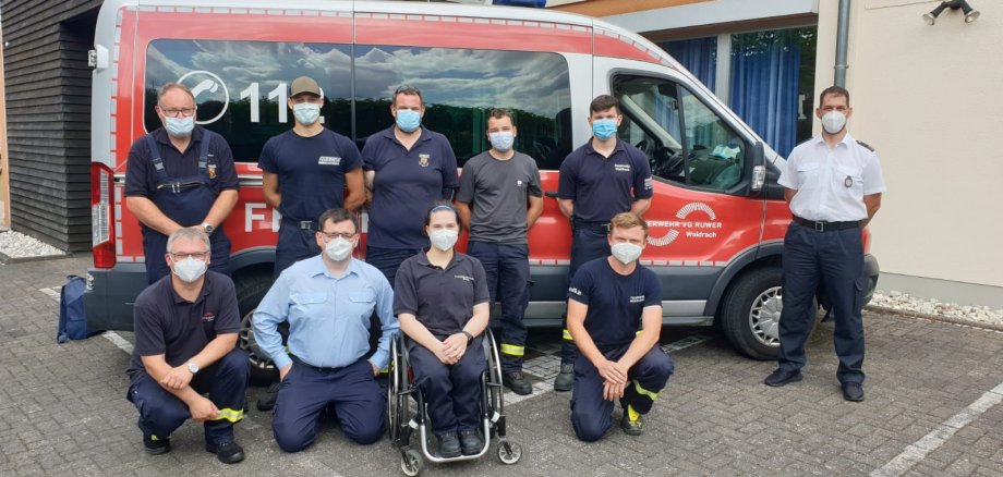 Mitglieder der Feuerwehr mit Masken vor Feuerwehrauto der VG Ruwer