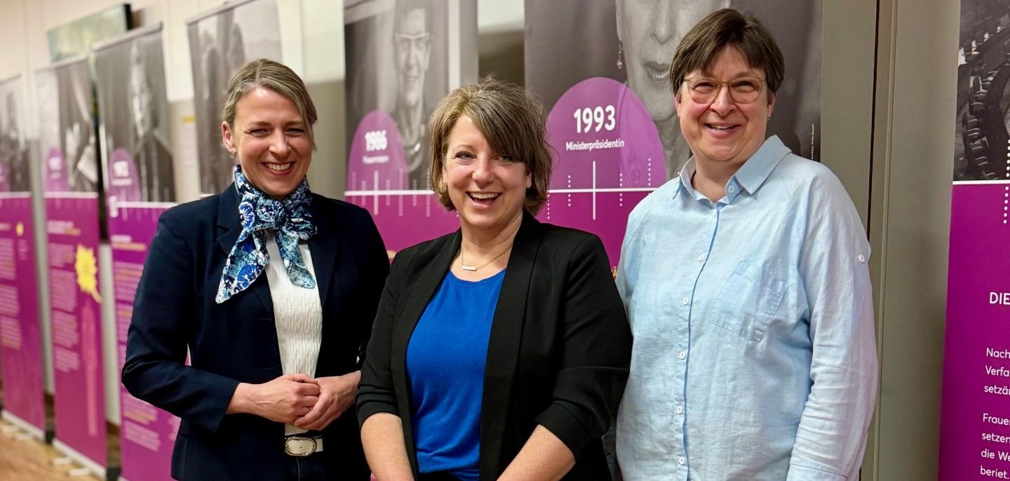 3 Frauen stehen vor mehreren Roll-Up´s und lächeln in die Kamera