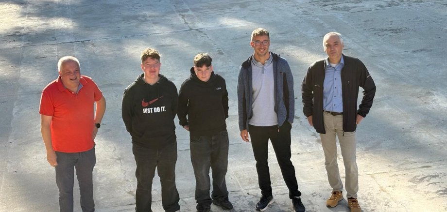 5 Personen lächeln bei einer Begrüßung in die Kamera