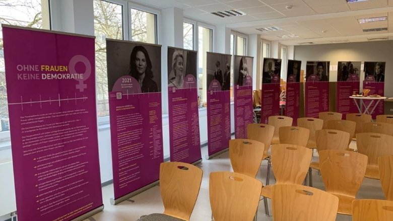 Raum mit Frauenwahlrechtsplakaten und Stühlen